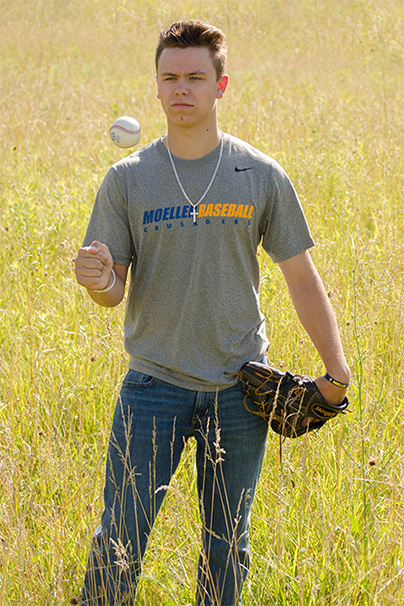 senior guy with baseball and glove in grass field