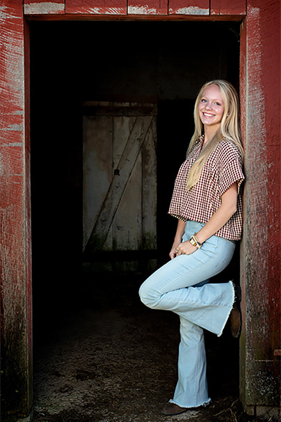 senior girl leaning in doorway of barn