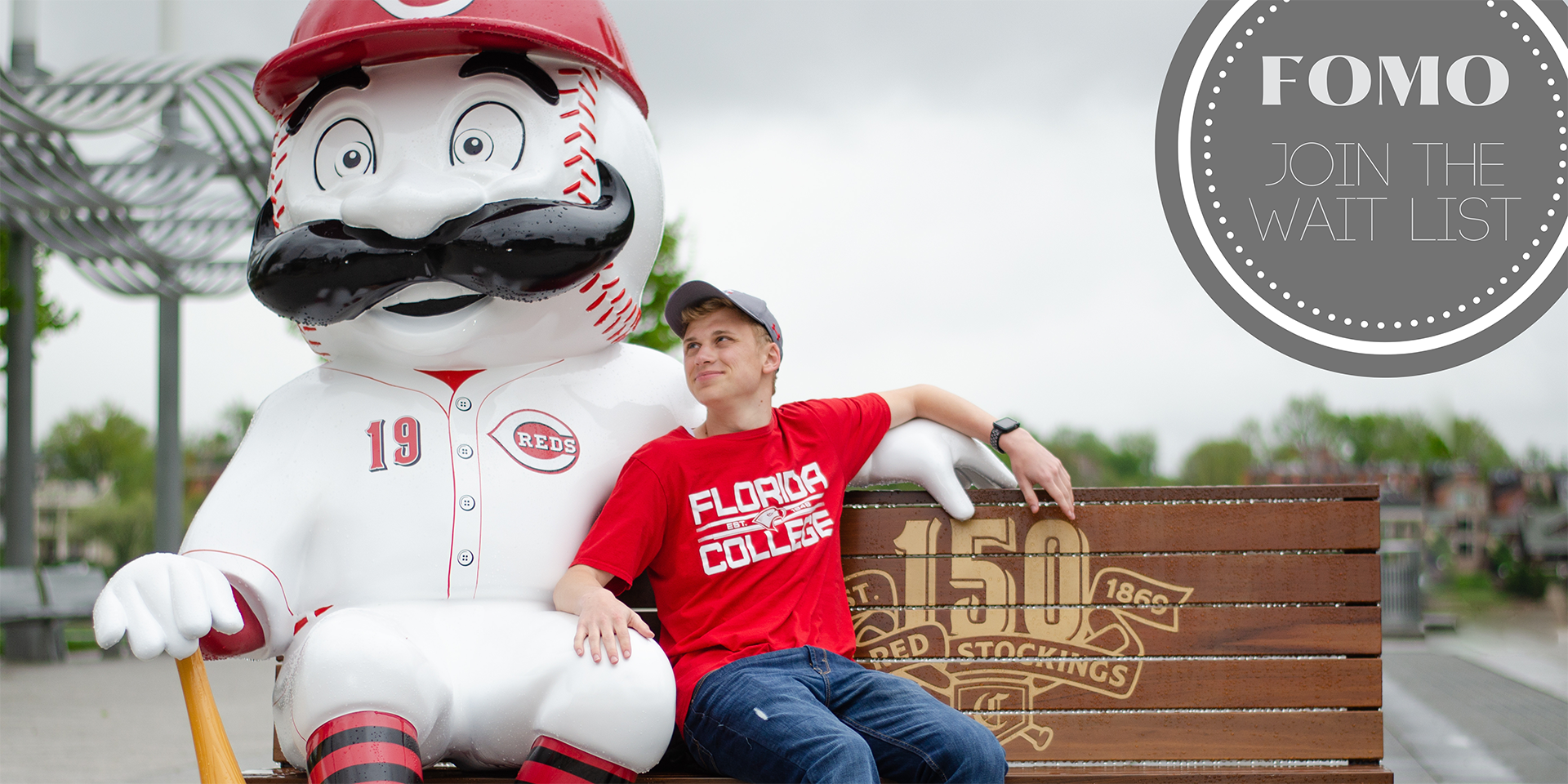 senior guy sitting on a bench with a statue of Mr. Redlegs