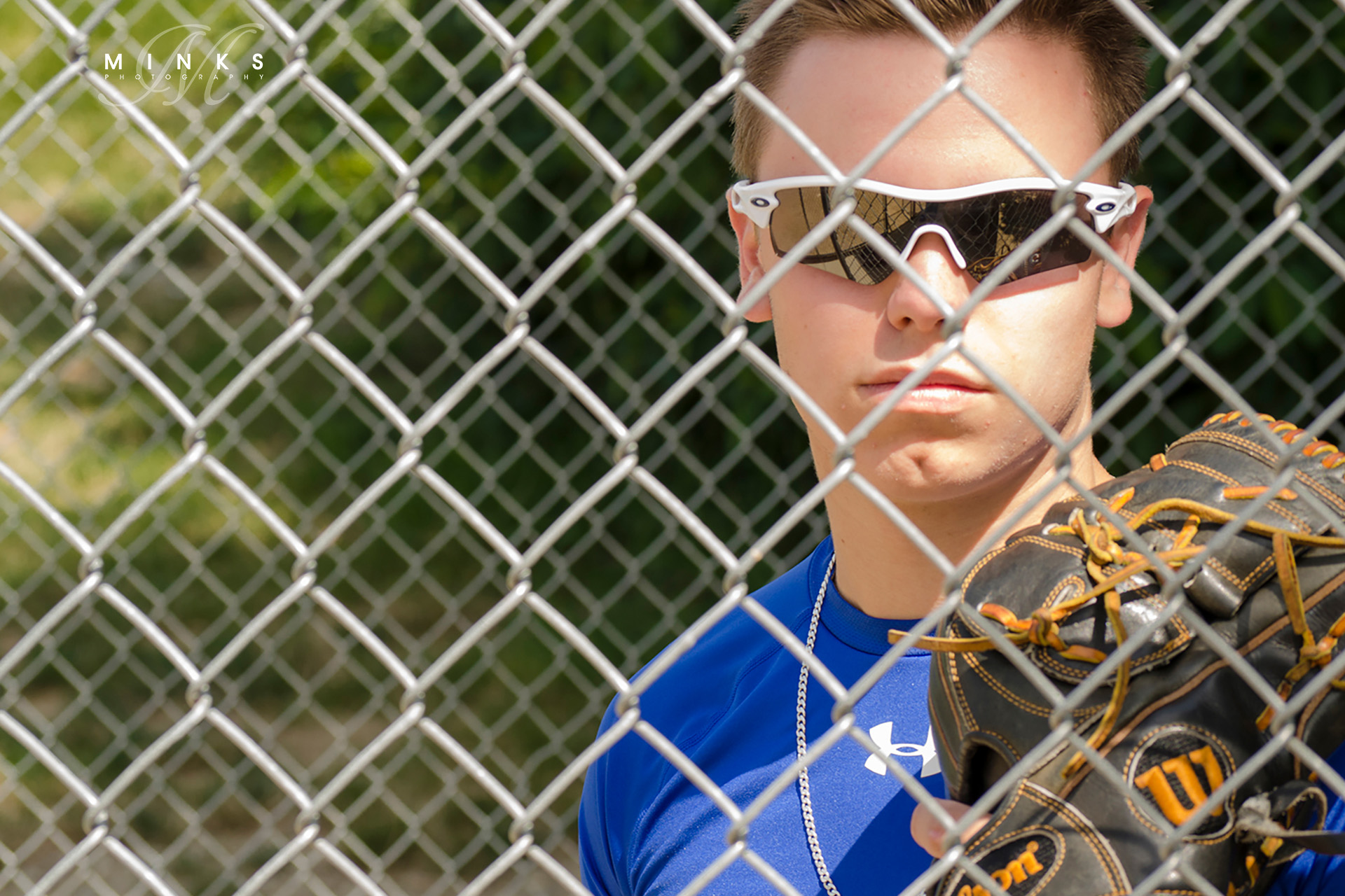 High School senior guy in dugout behind fence