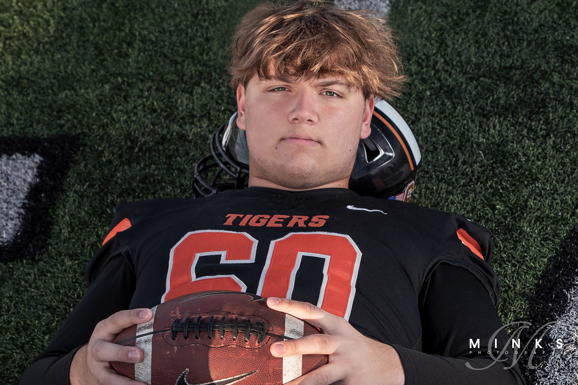 loveland ohio football player senior picture laying on field holding a football